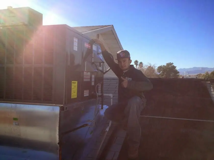HVAC technician performing Air Duct Cleaning on a rooftop unit in Richland